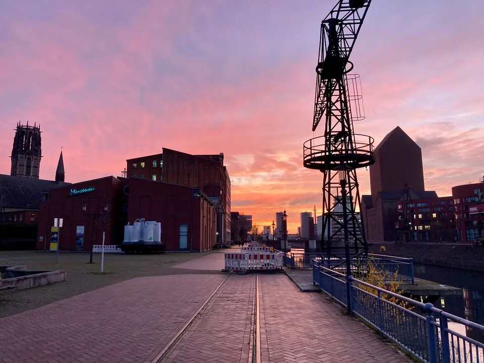 Lebhafter Sonnenuntergang über dem Duisburger Innenhafen, der industrielle Architektur und eine ruhige Skyline-Ansicht zeigt.