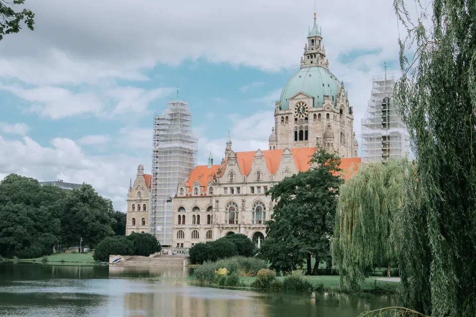Historisches Gebäude mit Kuppel und rotem Dach am Ufer eines ruhigen Sees, das schöne Architektur zeigt.