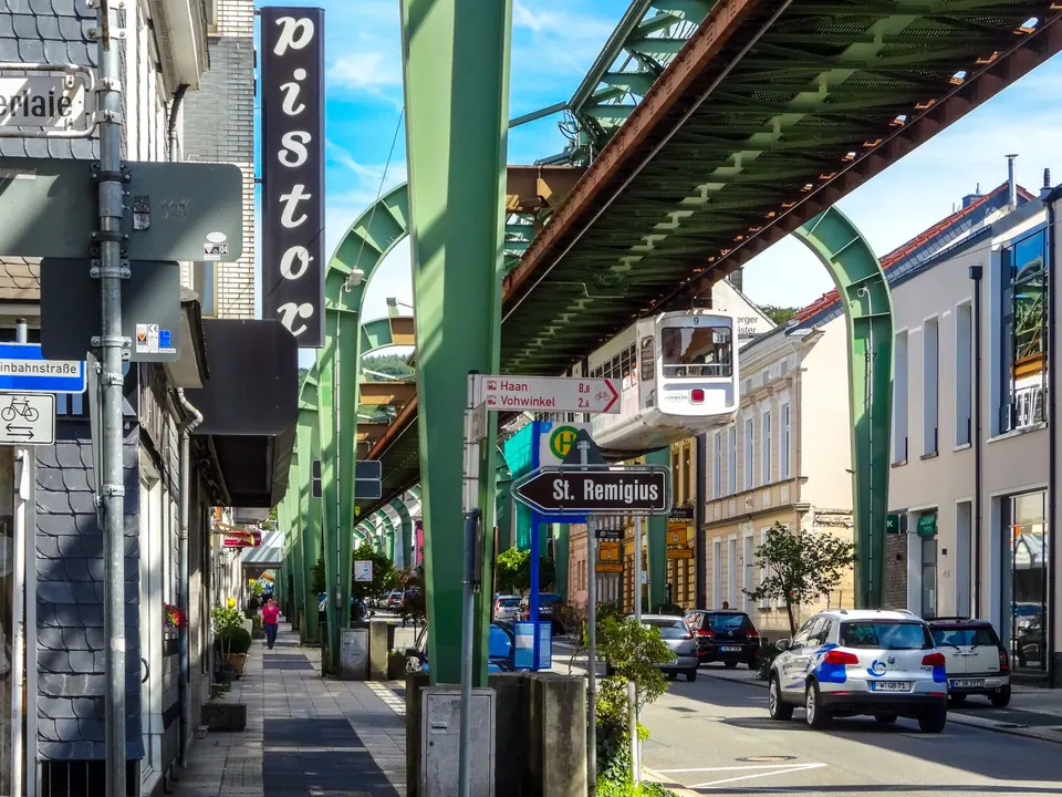 Ikonische Wuppertaler Schwebebahn über einer geschäftigen Stadtszene in Deutschland.